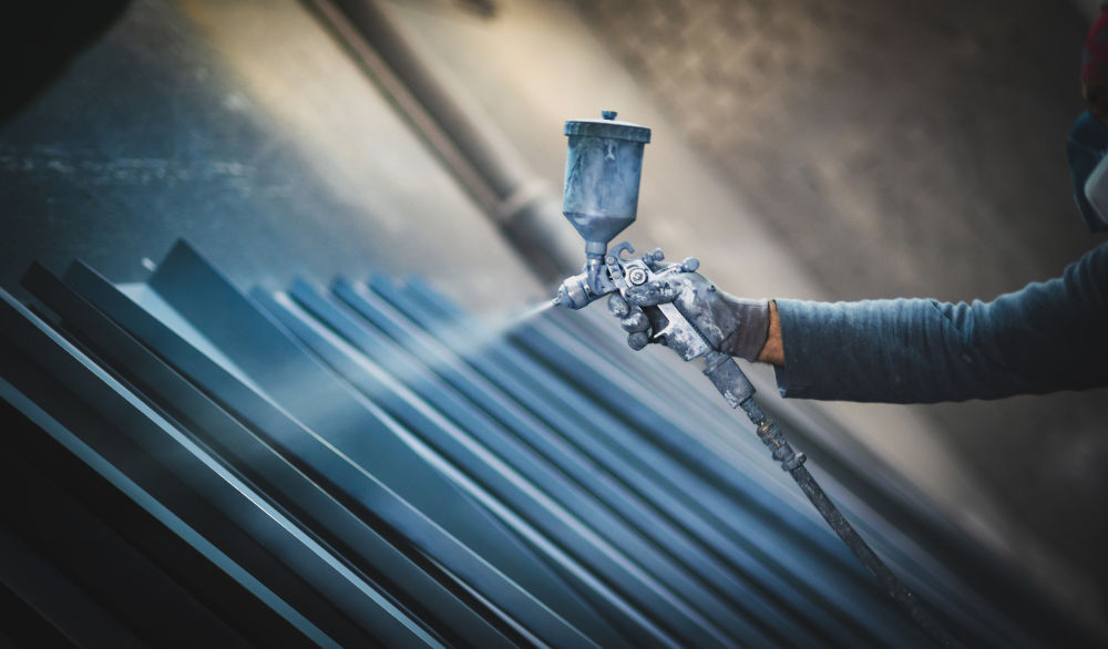 Contractor applying spray coating to metal products with a high-pressure spray gun